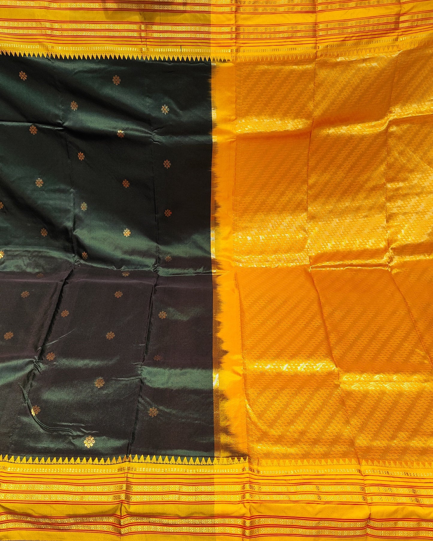 A close-up of a traditional Indian silk saree fabric, showing a vibrant orange body with a wide black border and a yellow-gold patterned pallu.