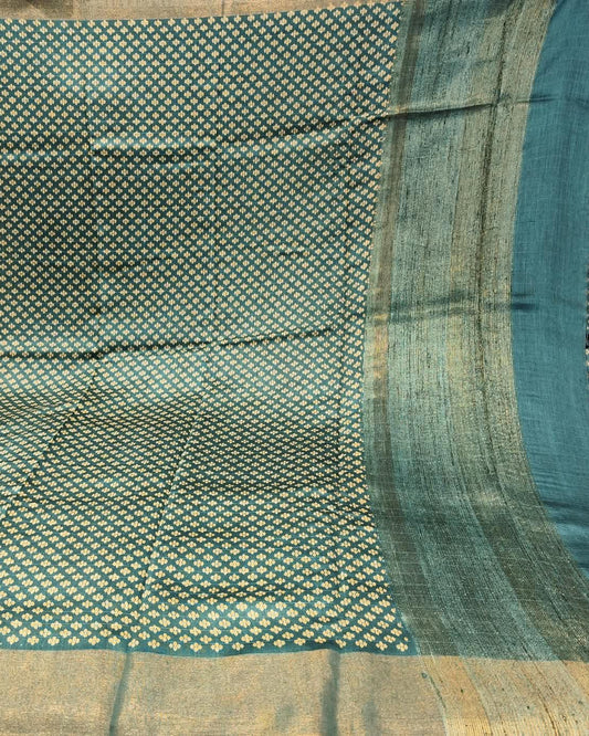 A close-up of a Tussar Silk Saree | Green | Digital Print featuring a teal blue body with a dense pattern of small gold and white motifs, and a wide beige-gold border.