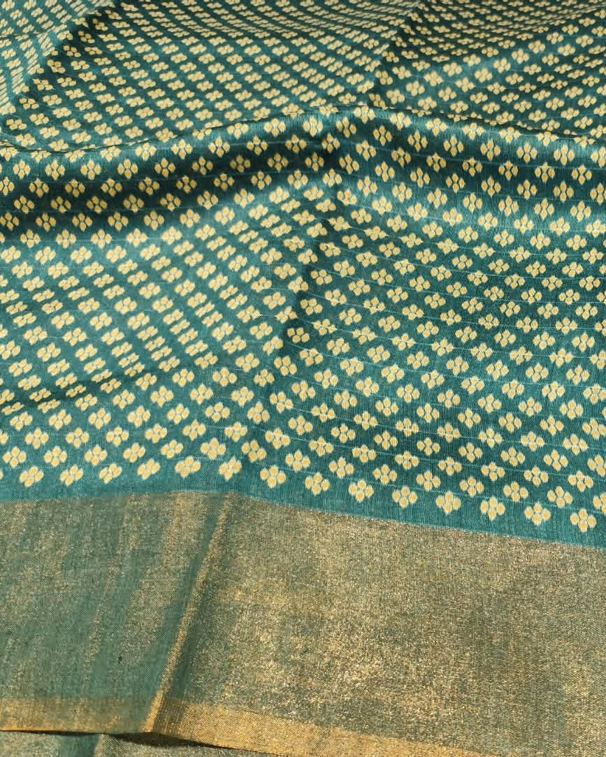 A close-up of a teal Tussar Silk Saree | Green | Digital Print with a repeating cream geometric pattern and a wide metallic gold border.