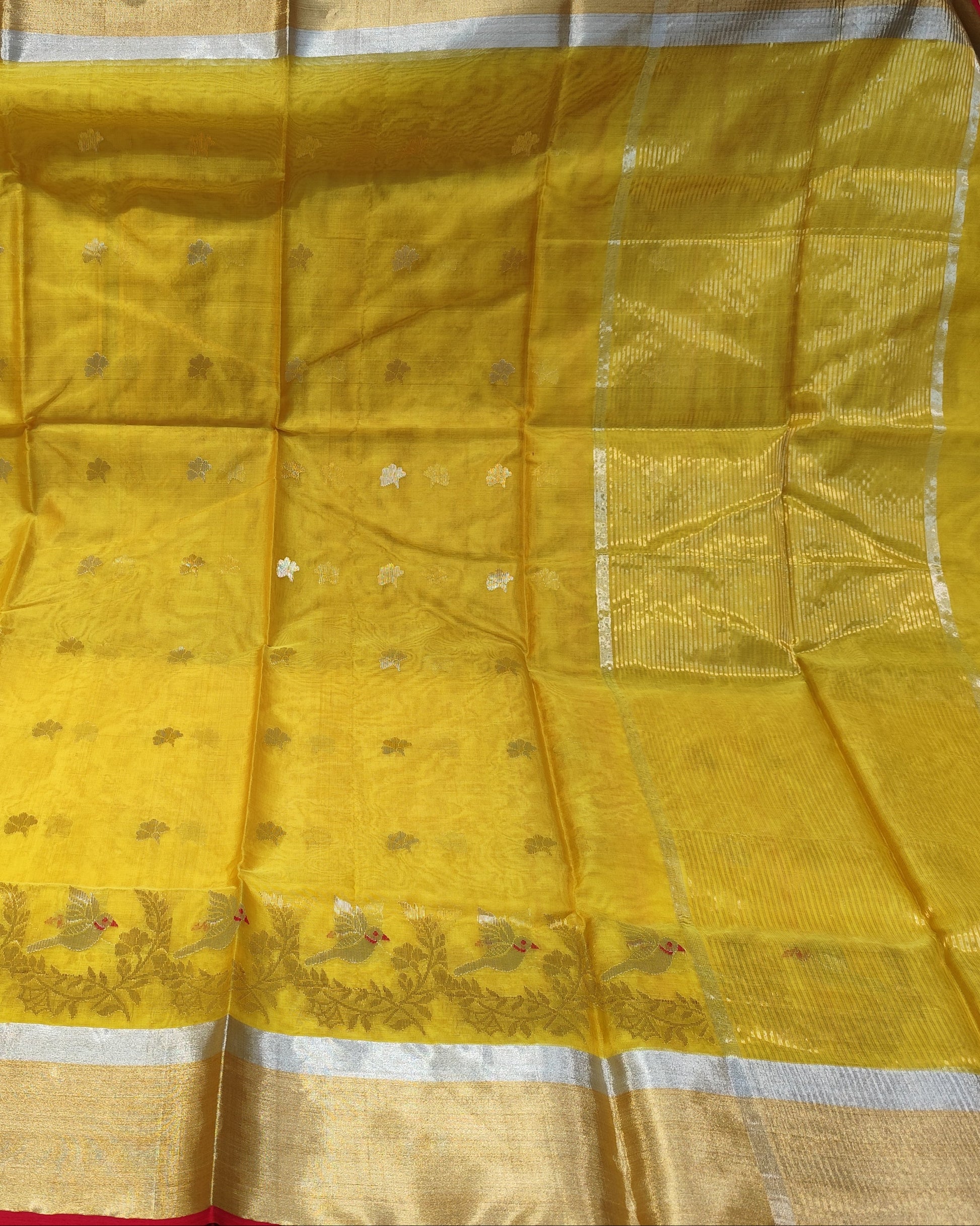 A yellow chanderi silk saree with a wide gold and silver border and small metallic motifs, held up to display its full pattern and texture.