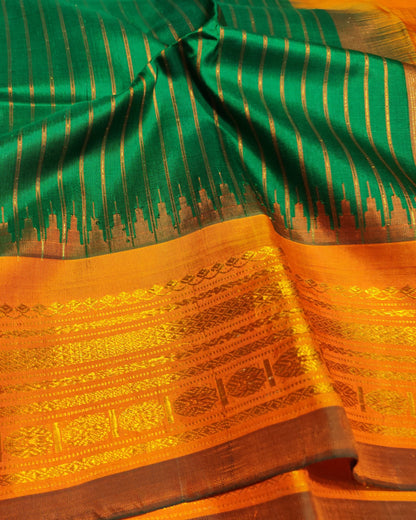 A close-up of a richly patterned Gadwal sari with a vibrant green body featuring vertical metallic gold stripes, a wide golden-orange border with intricate woven motifs, and a dark brown zari edge.