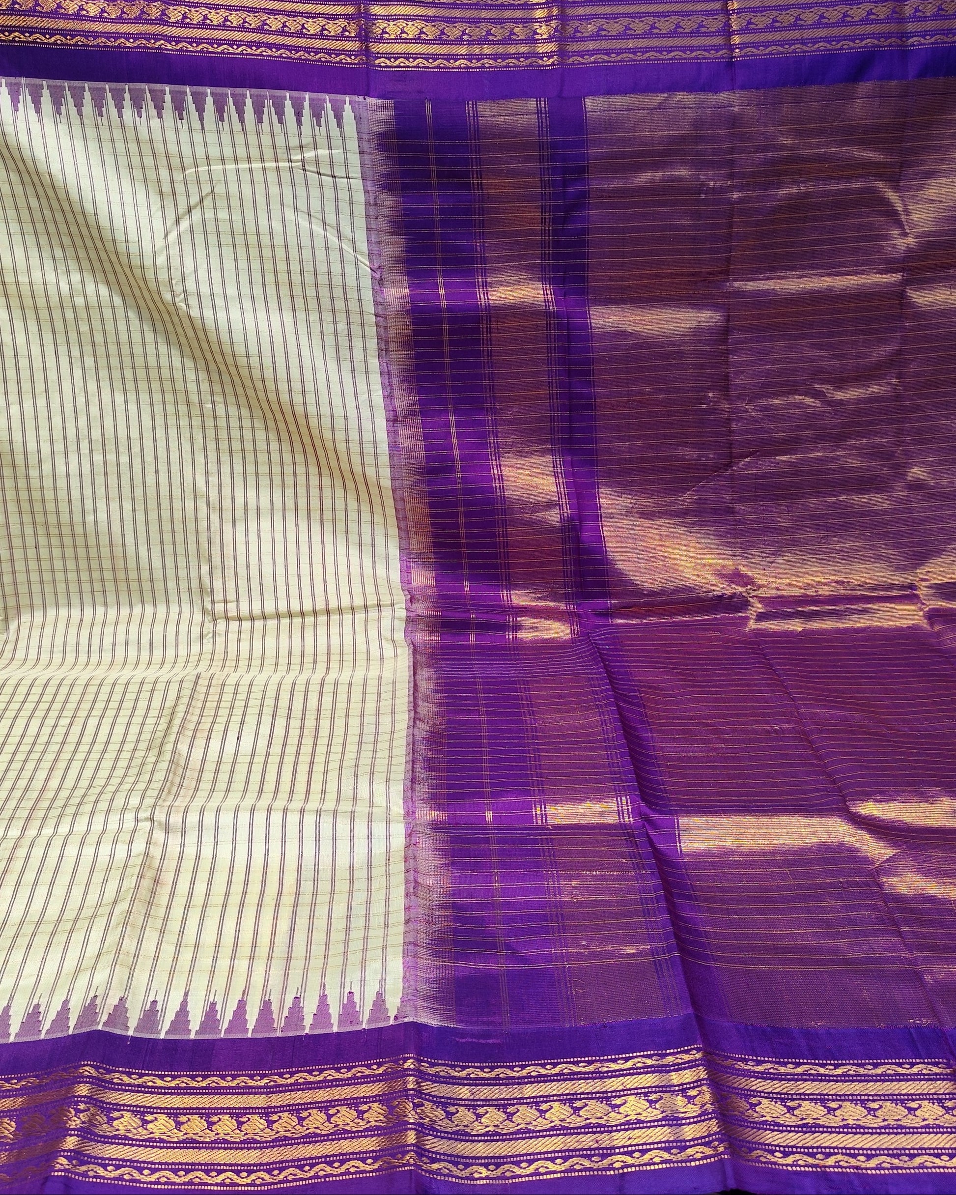 A purple and beige striped silk saree with gold zari detailing, displayed with its pallu draped over the side.