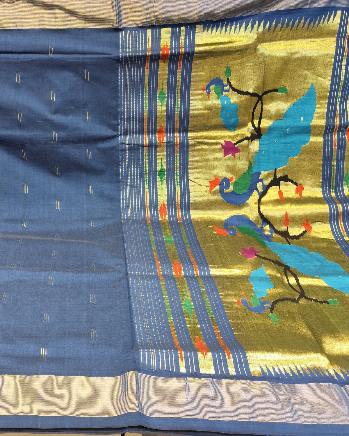 A blue and gold silk saree with woven metallic motifs and a vibrant border featuring blue birds and colorful floral details, displayed flat.