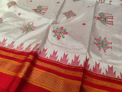 A close-up of a off white Ilkal silk saree with red and green embroidered motifs and a wide red border featuring gold zari-style detailing and a red geometric pattern.