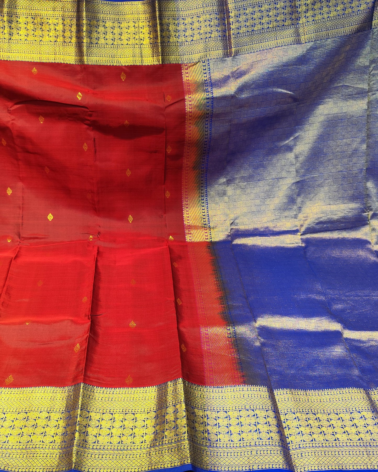 A red and blue saree with Kanjeevaram Red & Blue gold zari borders and motifs, held up to display its full pattern and fabric quality.