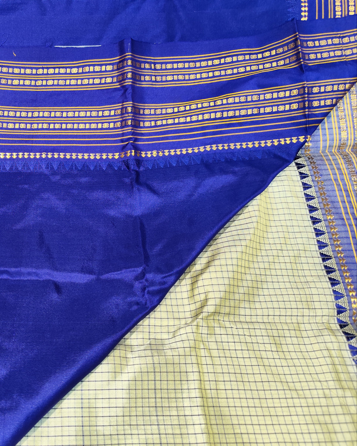 A close-up of a Narayanpeth Checks Off White 1 and royal blue saree, featuring a wide border with gold and white woven patterns and a contrasting light yellow-green body with a fine grid pattern.
