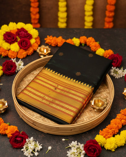 A folded Narayanpeth Green silk saree with a wide golden-yellow border featuring intricate red and gold zari patterns, displayed on a reflective light-colored surface.