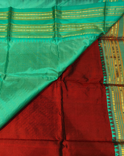 A folded Narayanpeth Maroon & Blue Saree 1silk saree fabric with a vibrant green body, a deep red underlayer, and a yellow-gold zari patterned border.