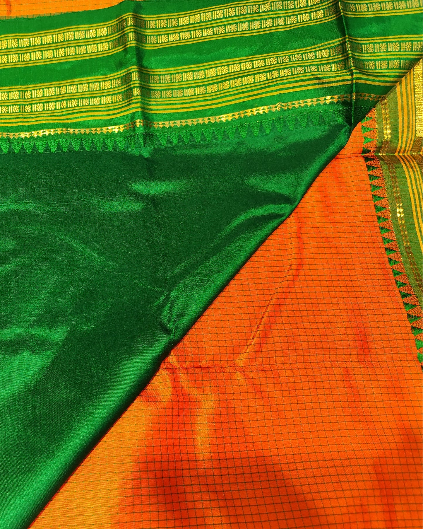 A close-up of a green and orange Narayanpeth silk saree with intricate gold zari woven borders and a geometric patterned pallu.