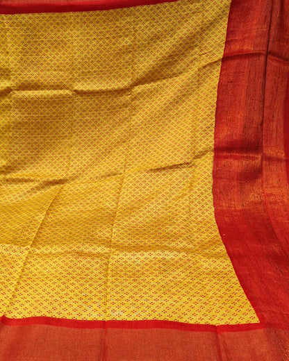 A close-up of a yellow and red woven Yellow_and_Red_Tussar_Silk_Saree_3 likely a saree or textile, featuring a yellow body with a repeating small motif and a wide red border.