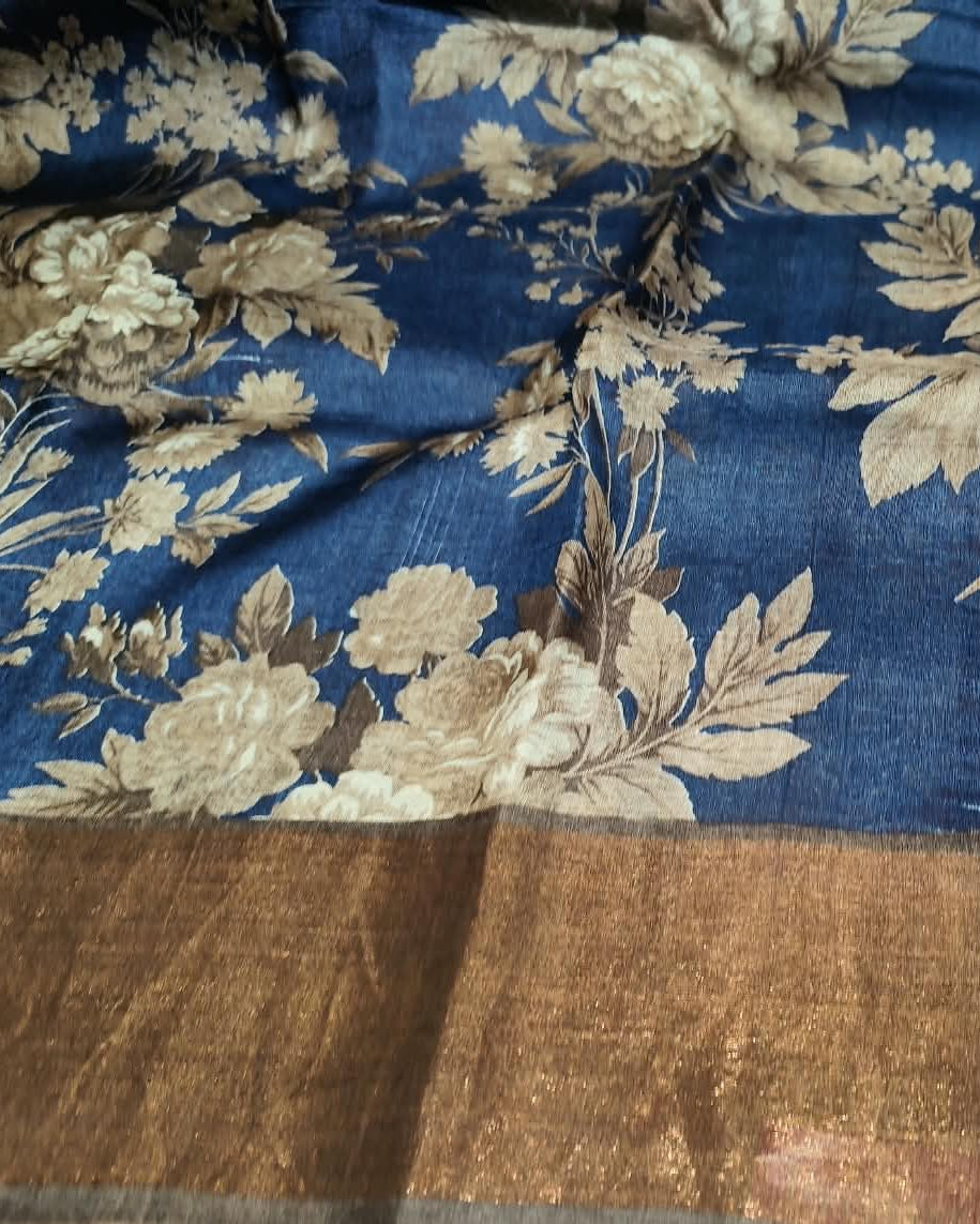 A close-up of a blue fabric with a beige floral brocade pattern and a wide metallic gold border Tussar Silk Saree | Floral Print Blue.
