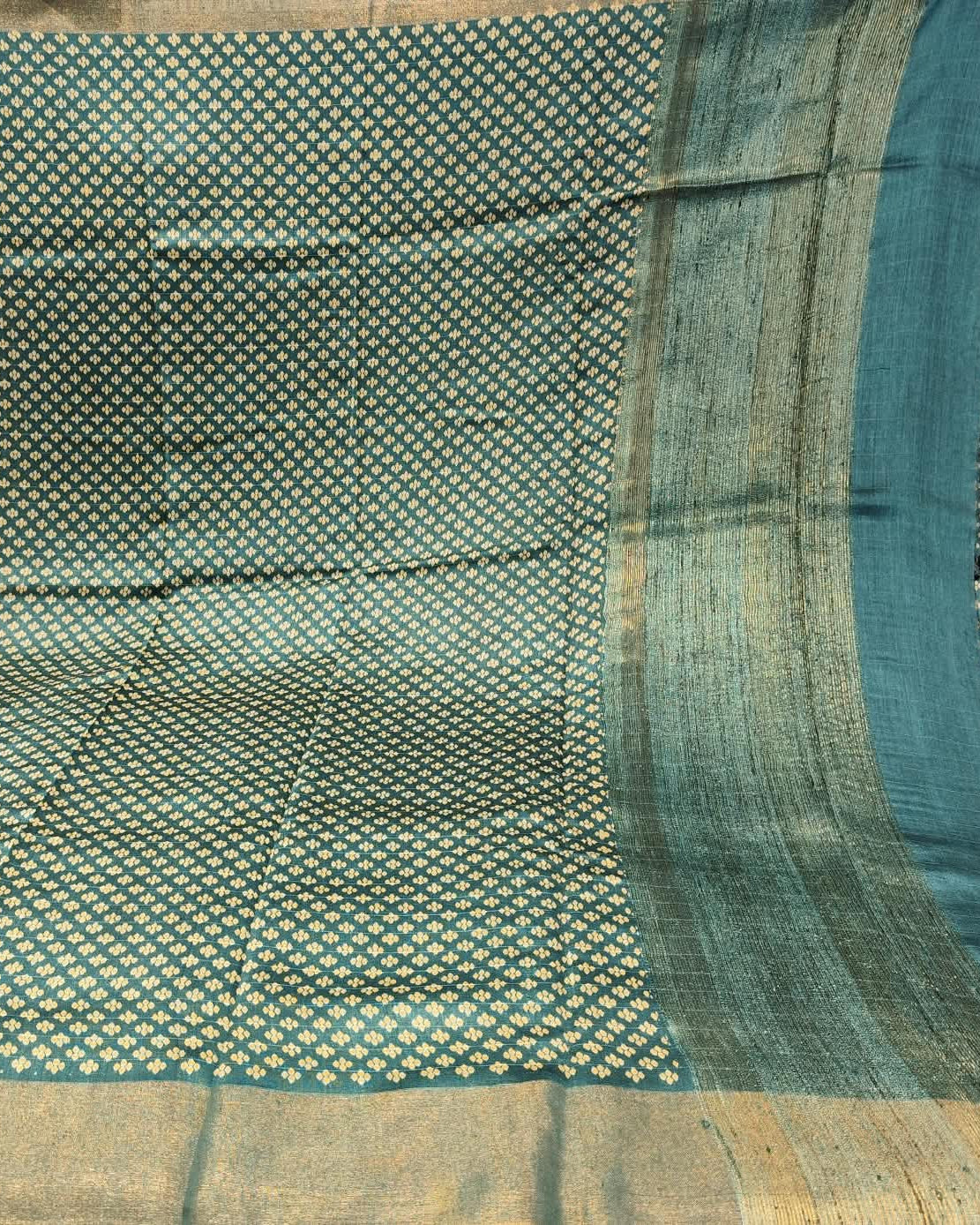 A close-up of a Tussar Silk Saree | Green | Digital Print featuring a teal blue body with a dense pattern of small gold and white motifs, and a wide beige-gold border.