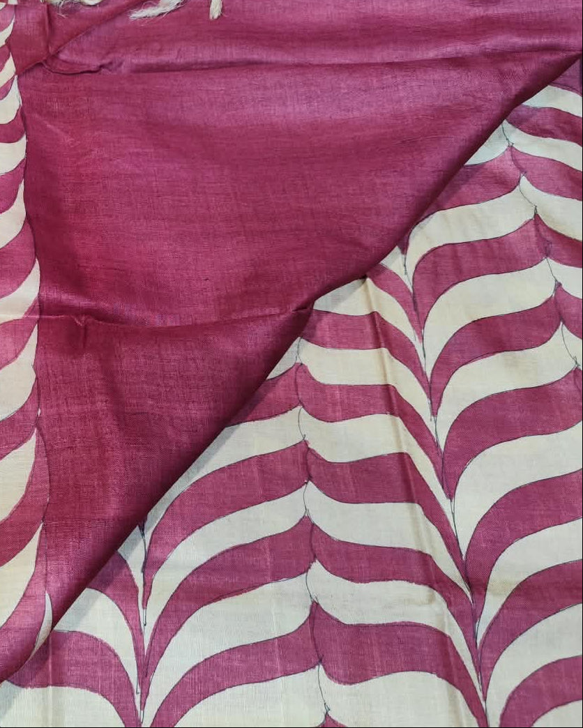 A close-up of a folded textile, likely a sari or fabric panel, showing a magenta-pink and off-white wavy striped pattern alongside a solid magenta section and a beige border.